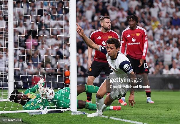 Brennan Johnson of Tottenham Hotspur scores his team's first goal past Andre Onana of Manchester United as Luke Shaw of Manchester United looks on...