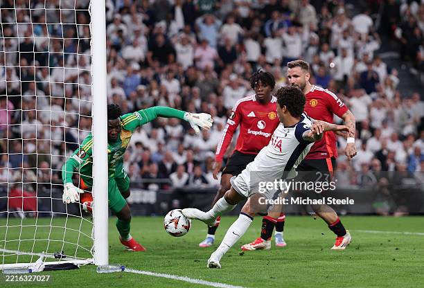 Brennan Johnson of Tottenham Hotspur scores his team's first goal past Andre Onana of Manchester United as Luke Shaw of Manchester United looks on...