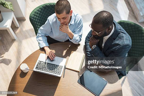 deux professionnels collaborant à l’aide de la technologie dans un environnement de bureau lumineux - face à face photos et images de collection