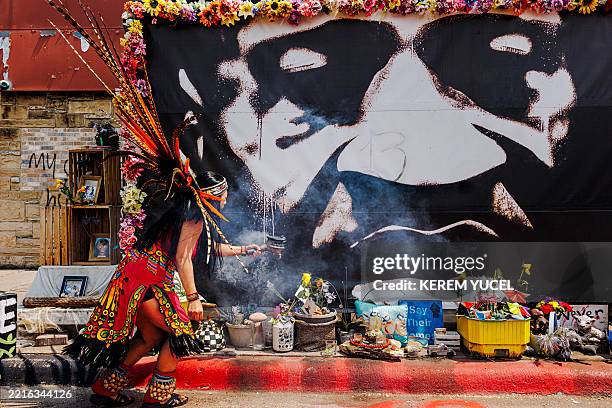 An Aztec dancer from the KetzalCoatlicue dance group performs a ceremonial blessing in front of a mural of George Floyd at George Floyd Square in...