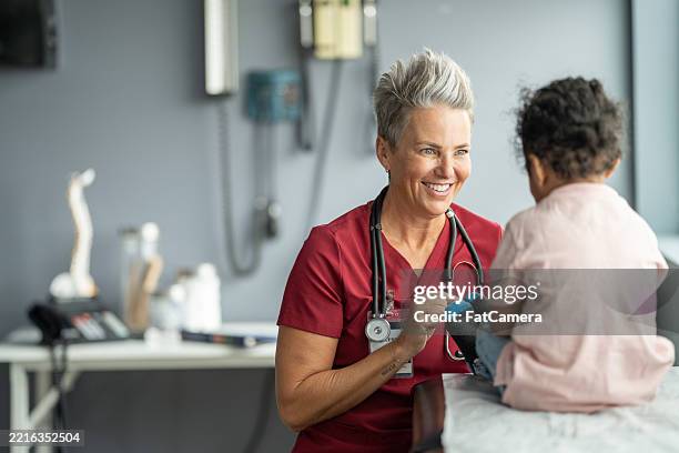 enfermera amigable interactuando con un niño pequeño durante una cita médica pediátrica - hospital infantil fotografías e imágenes de stock