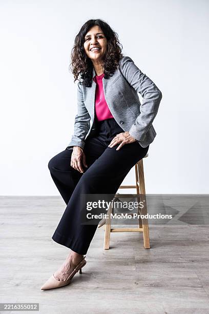 studio portrait of businesswoman smiling on white background - tabouret photos et images de collection