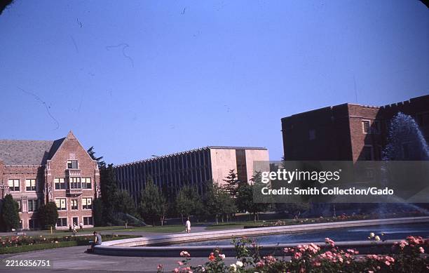 Drumheller Fountain surrounded by blooming rose beds, with a mix of Collegiate Gothic and modern academic buildings on the University of Washington...