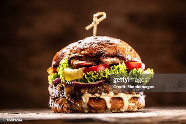 delicious burger with lettuce salad, tomatoes and dressing on wooden cutting board - hamburger stock pictures, royalty-free photos & images