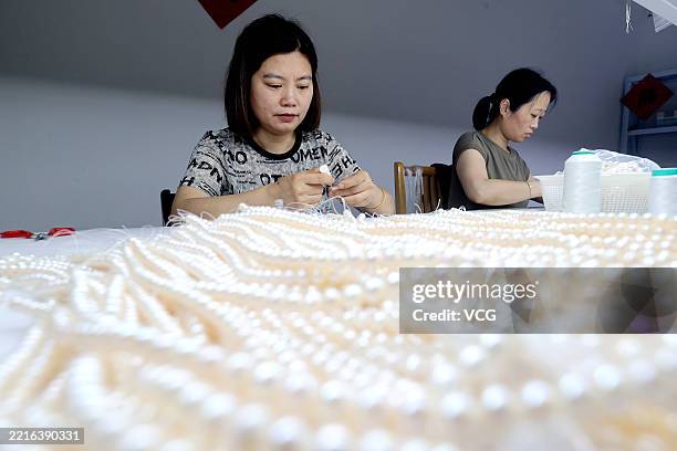 Employees produce pearl jewellery at a workshop on May 21, 2025 in Huzhou, Zhejiang Province of China. The Deqing Freshwater Pearl Mussels Composite...