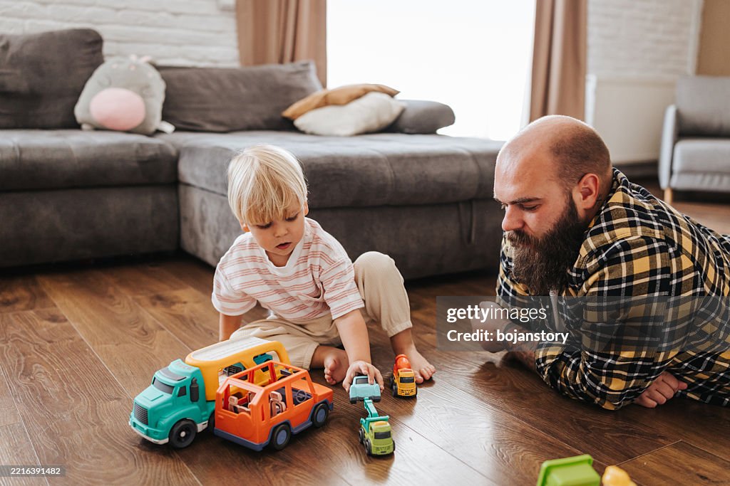Man enjoys playing time with his little son at home