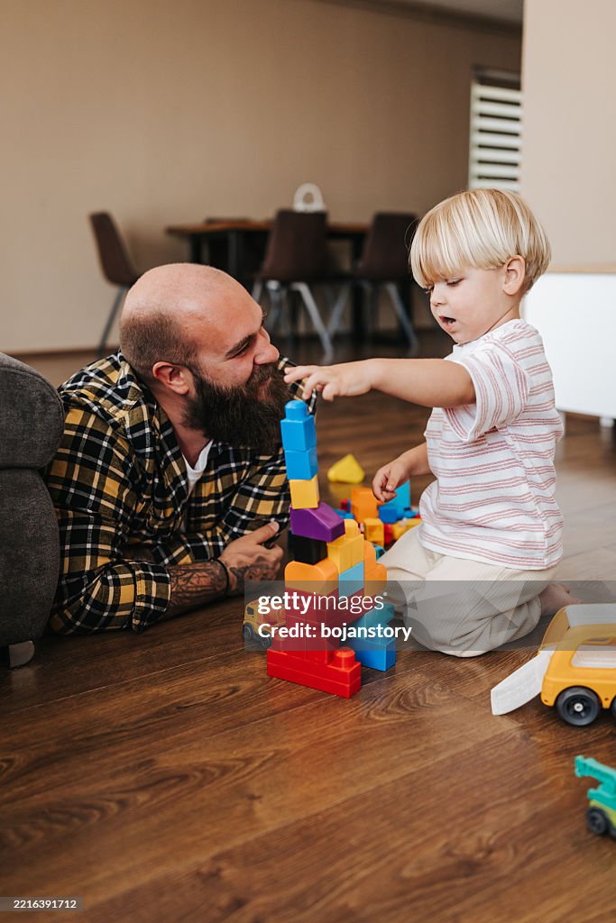Man enjoys playing time with his little son at home