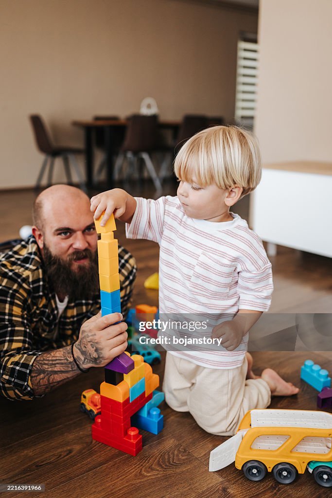 Man enjoys playing time with his little son at home