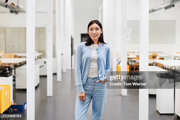 portrait of a female architecture student standing confidently in a bright modern classroom - mani in tasca foto e immagini stock
