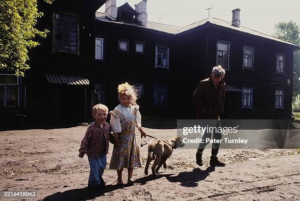 Man, two children and a dog standing outside a building in Novokuznetsk, Siberia, Russia, June 1991.