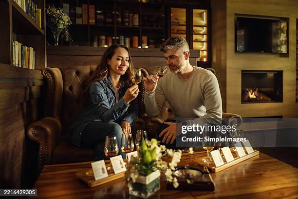 a young couple enjoying rum, cognac or whiskey in a stylish bar - whiskey tasting stock pictures, royalty-free photos & images