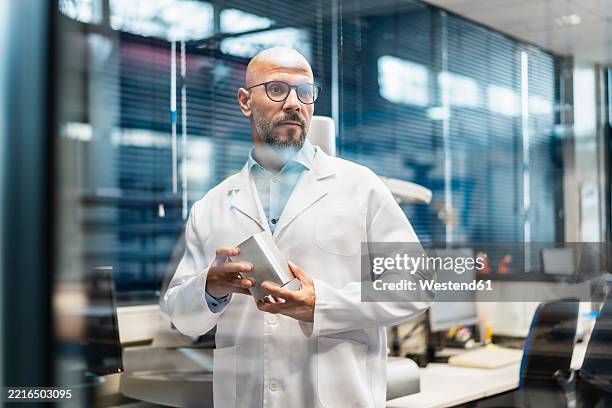 scientist in a laboratory wearing a lab coat and glasses - scientist portrait stock pictures, royalty-free photos & images
