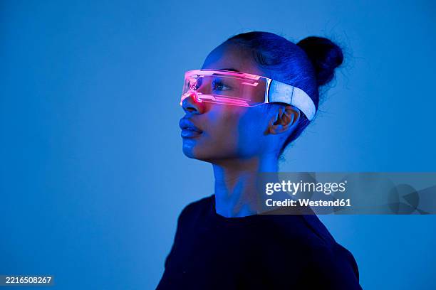 person wearing vr glasses in a futuristic style with blue lighting in a studio - digitalisation photos et images de collection