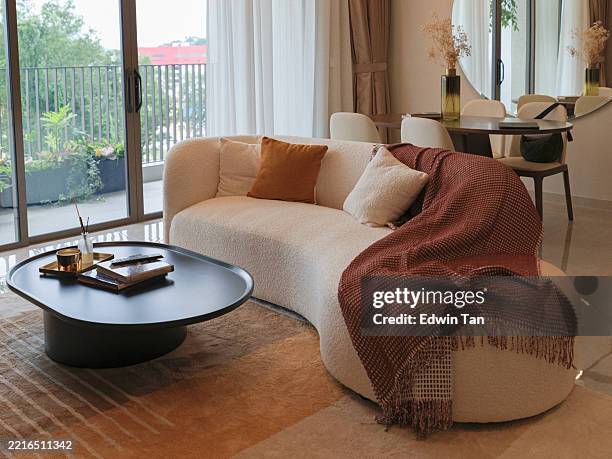 modern cozy living room with curved sofa and warm natural light - coffee table stock pictures, royalty-free photos & images
