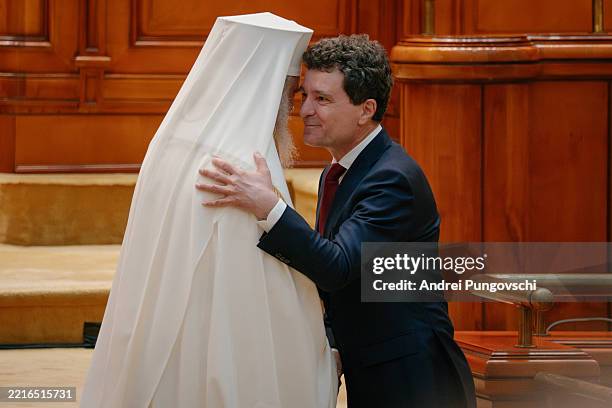 Romanian President Nicusor Dan embraces Romanian patriarch Daniel after taking the oath as new president in the Romanian parliament, on May 26, 2025...
