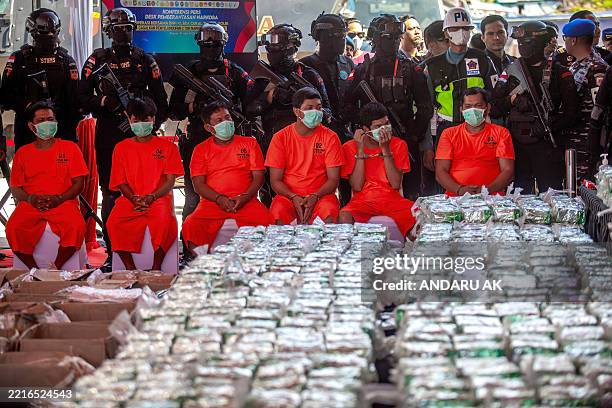 Suspects are seen alongside seized crystal methamphetamine during a press conference by Indonesia's National Narcotics Agency officials in Batam,...
