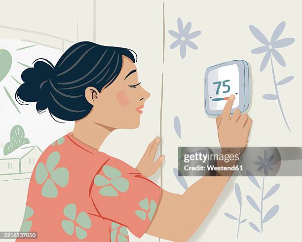 Woman Adjusting A Smart Thermostat In A Modern Home, 照片檔