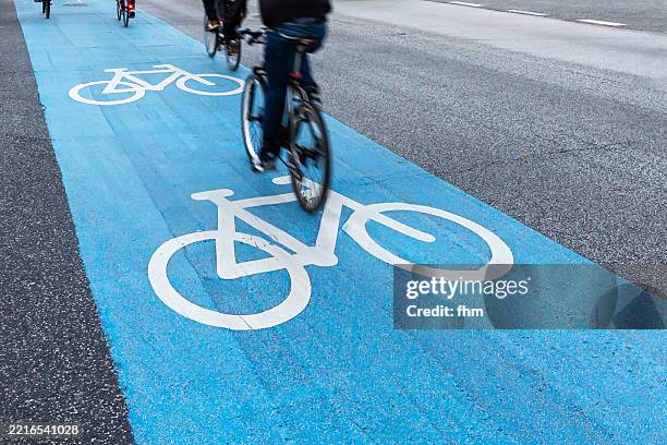 blue bicycle path on a road with with cyclists - carril para ciclistas fotografías e imágenes de stock