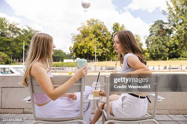 two best friends relaxing with cold drinks in berlin with the tv tower in the background - terrasse-de-café photos et images de collection