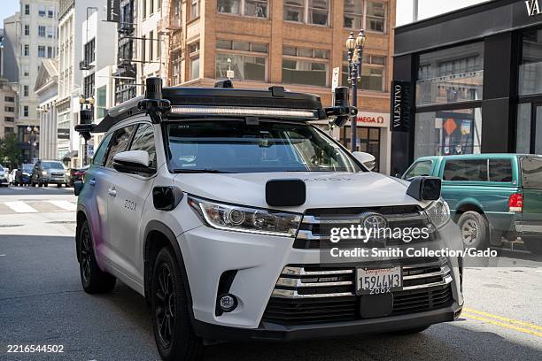 Zoox autonomous test SUV with rooftop lidar and corner-mounted sensors on city street near luxury shops, Union Square, San Francisco, California,...