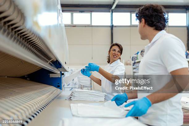 industrial laundry workers folding linens efficiently - laundromat stock pictures, royalty-free photos & images