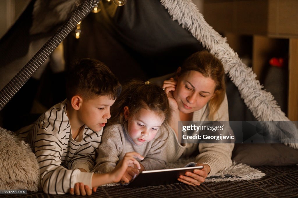 Family Bonding with a Digital Tablet in a Cozy Blanket Fort