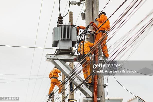 electric utility workers repairing power lines on elevated infrastructure - rede elétrica imagens e fotografias de stock