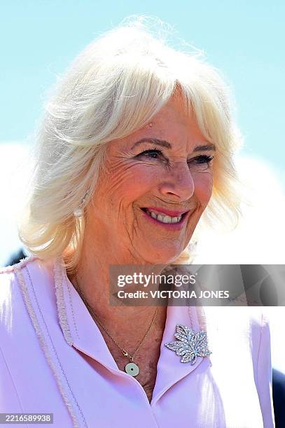Britain's Queen Camilla, wearing a maple leaf brooch, reacts as she and Britain's King Charles III are greeted after arriving at Macdonald-Cartier...