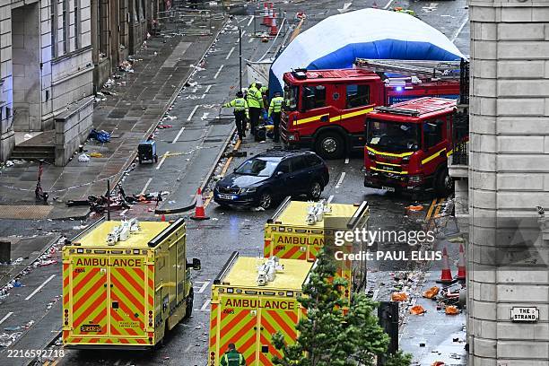 Police officers cover with an inflatable tent, behind a firefighter vehicle, the tents delimiting the scene of an incident in Water Street, on the...