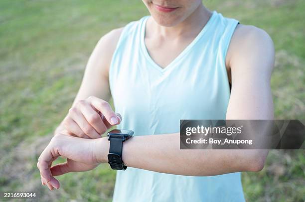 cropped shot view of runner woman checking fitness progress on her smart watch. - poignet photos et images de collection