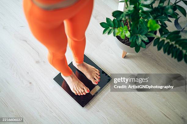 gros plan de la femme en vêtements de sport orange mesurer le poids sur la balance. - balance photos et images de collection