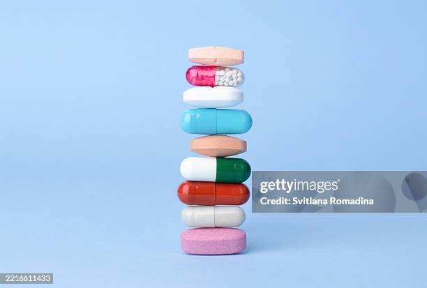 assorted pharmaceutical drugs balancing on each other, conceptional idea . blue background with copyspace - pharma stock-fotos und bilder