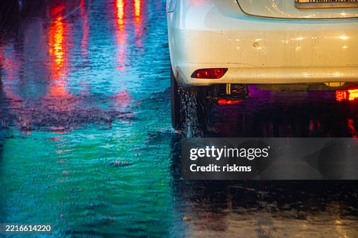 The back of a car driving in the rain on a wet road The back of a car driving in the rain on a wet road