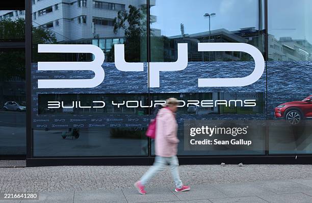 Woman walks past a dealership of Chinese electric car manufacturer BYD on May 23, 2025 in Berlin, Germany. BYD has overtaken Tesla in electric car...