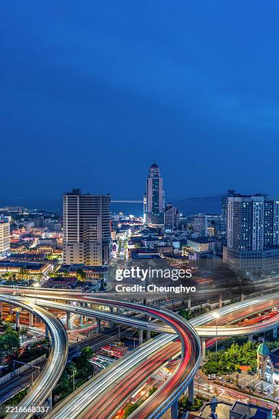 high angle view: the traffic of the elevated road in front of qingdao city skyline at twilight. qingdao city, shandong province, china - phare arrière de véhicule photos et images de collection