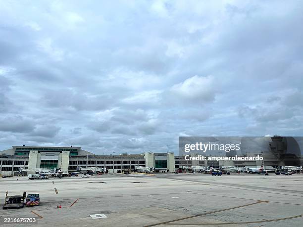 aeroporto internacional de miami com aviões estacionados na pista sob o céu nublado - aeroporto internacional de miami - fotografias e filmes do acervo