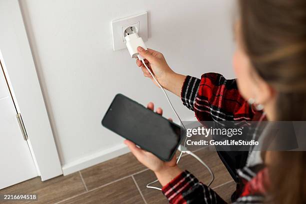 mujer cargando su teléfono móvil - cargador de móvil fotografías e imágenes de stock