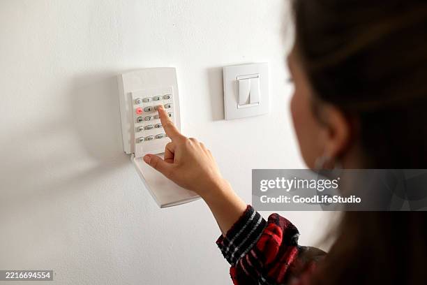 woman setting a home security alarm - burglar alarm stock pictures, royalty-free photos & images