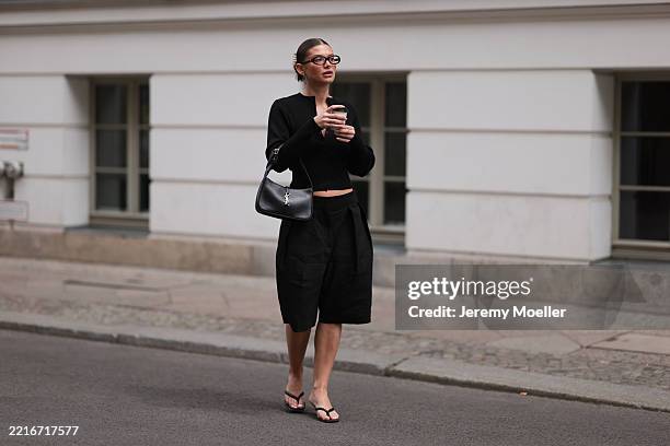 Sophia Geiss is seen wearing silver hoop earrings in two different sizes, oval brown glasses from Corlin, a silver nose ring, a black ribbed-knit...