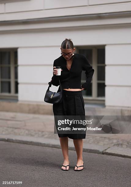 Sophia Geiss is seen wearing silver hoop earrings in two different sizes, oval brown glasses from Corlin, a silver nose ring, a black ribbed-knit...