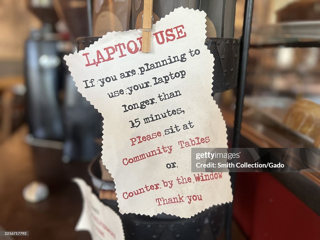 Laptop usage sign posted inside a coffee shop, reminding patrons to ...