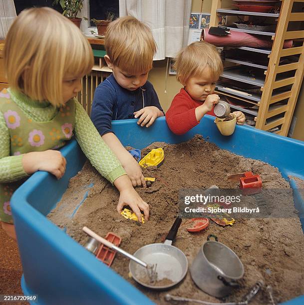 1960s day care. Three children are playing with toys in a box of sand at a preschool in Sweden 1969.