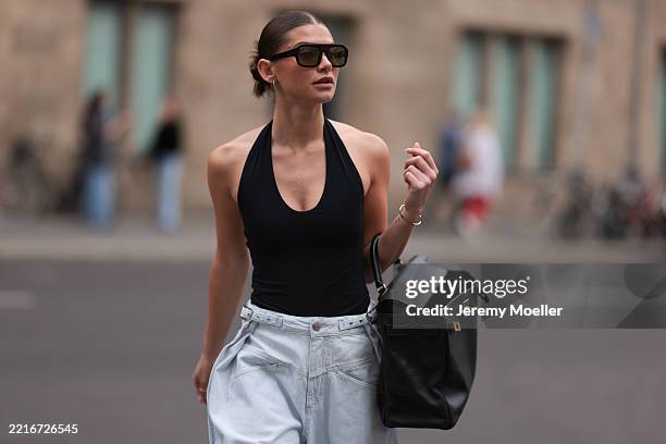 Sophia Geiss is seen wearing silver hoop earrings in two different sizes, large aviator sunglasses with a bold black frame and green lenses from...