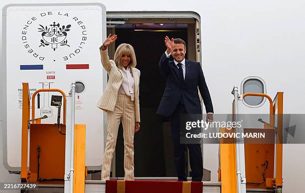 France's President Emmanuel Macron and his wife Brigitte Macron wave as they board their plane for departure following their visit to Vietnam at Noi...