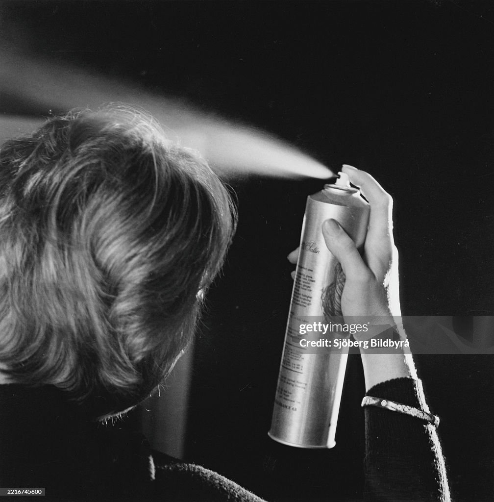 A woman spraying her hair. The use of hairspray exploded after that Farah Diba married the Shah of Ira...