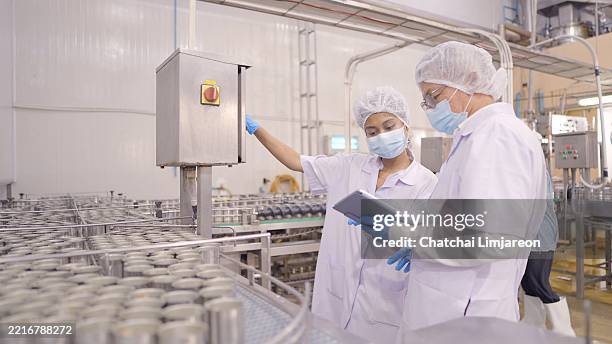 gli ingegneri stanno controllando il sistema del macchinario di una macchina per l'imballaggio di alimenti pronti al consumo in un impianto di lavorazione degli alimenti. dipendente che lavora nella linea di produzione per la lavorazione degli alimenti. co - fabbrica di produzione alimentare foto e immagini stock