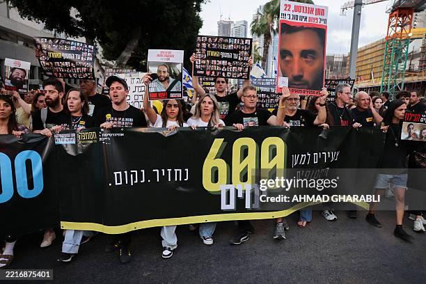 Relatives and supporters of Israeli hostages held captive in the Gaza Strip since the October 7 attack in southern Israel, hold their portraits and...