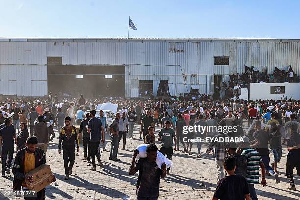 Displaced Palestinians ferry bags of food aid after storming a World Food Programme warehouse in Deir el-Balah in the central Gaza Strip on May 28,...