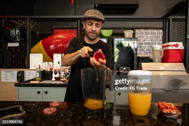 mid adult bartender preparing a juice at coffee shop or restaurant - juice bar stock pictures, royalty-free photos & images