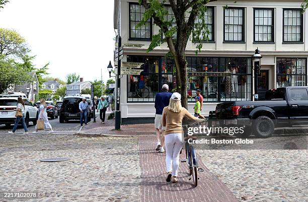 Nantucket, MA Cyclists walk their bikes across Main Street on May 28, 2025.